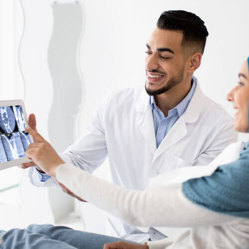 Médico ortodontista mostrando check-up digital em tablet para paciente em clínica odontológica em Guarulhos